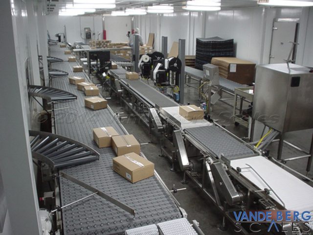The center of the image shows two automatic box labelers in a warehousing facility.